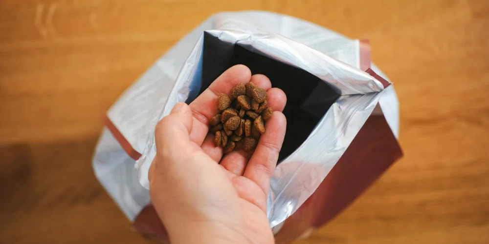 A picture of a man scooping out some pet food out of a bag